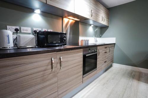 a kitchen with wooden cabinets and a microwave at Great location Modern refurbishment Free parking in Leeds