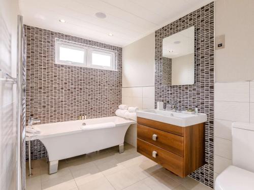 a bathroom with a tub and a sink and a mirror at 2 Bed in Ilfracombe 87361 in Kentisbury