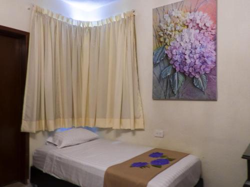 a bedroom with a bed and a painting on the wall at Hotel Boutique Flores y Gemas in Mérida