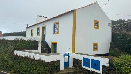 ein weißes Haus mit blauen Türen auf einem Hügel in der Unterkunft Casa da Lapa in Angra do Heroísmo