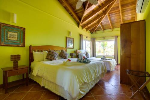 a bedroom with two beds in a room with yellow walls at Laru Beya All Inclusive Resort in Placencia Village