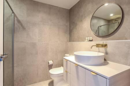 a bathroom with a sink and a mirror and a toilet at Lavish Coastal 2-Bed with Stunning Ocean Views in Batemans Bay