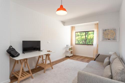 a living room with a couch and a desk with a tv at River Breeze in Almada Velha in Almada