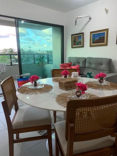 uma sala de jantar com uma mesa e cadeiras e um sofá em Apartamento a Beira-Mar - Praia do Francês em Marechal Deodoro