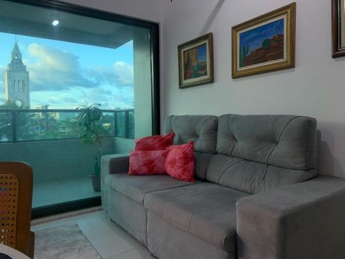 a living room with a couch and a large window at Apartamento a Beira-Mar - Praia do Francês in Marechal Deodoro