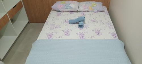 Una cama con una tabla azul con flores. en Casa da Marilú, en Florianópolis