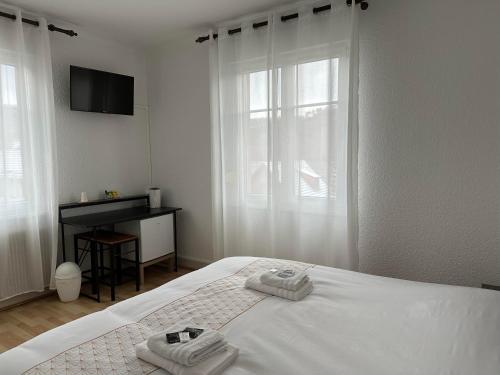a white bedroom with two towels on a bed at Au Wachtfels in Obersteinbach