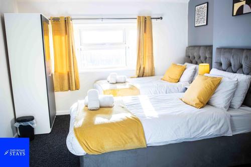 a bedroom with two beds and a window at 2ndHomeStays-Walsall- A Charming 3-Bedroom Home in West-Midlands, Suitable for long Stay Contractors-Families-Group of Friends on Holiday, 7 mins to J10 M6 and 21 mins to Birmingham in Bloxwich