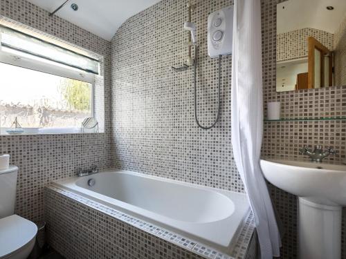 a bathroom with a white tub and a sink at 3 Bed in Sheringham 90701 in Sheringham