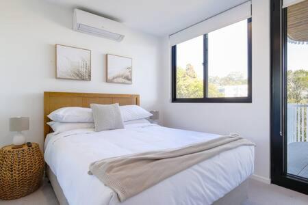 Habitación blanca con cama y ventana en Elegant 2-Bed Apartment with Stunning Views, en Batemans Bay