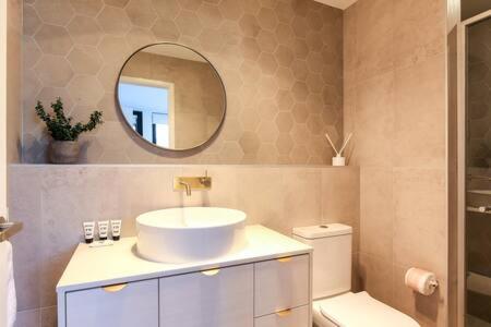 y baño con lavabo, espejo y aseo. en Elegant 2-Bed Apartment with Stunning Views, en Batemans Bay