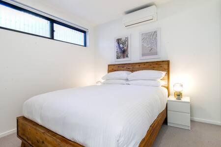 a white bedroom with a large bed and a window at Magnificent 1-Bed with BBQ and Views in Batemans Bay