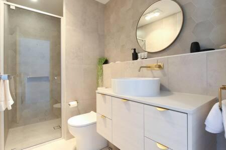 La salle de bains est pourvue de toilettes, d'un lavabo et d'un miroir. dans l'établissement Magnificent 1-Bed with BBQ and Views, à Batemans Bay