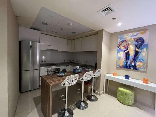 una cocina con una isla de cocina con sillas y una pintura en شقة في برج رافال بإطلالة ساحره en Riad