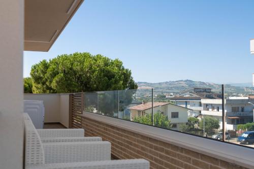 a balcony with white chairs and a view of a city at Residence LeoMare in Martinsicuro