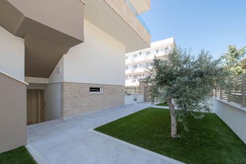 a courtyard with a tree and a building at Residence LeoMare in Martinsicuro