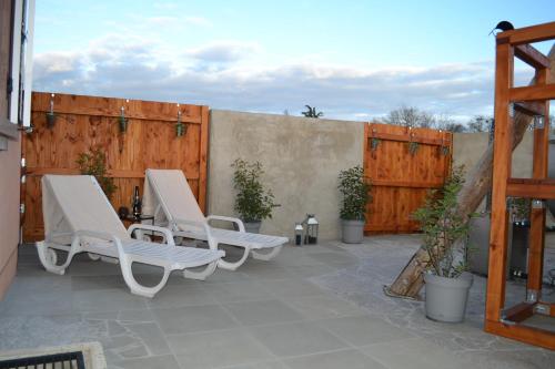 eine Terrasse mit 2 Liegestühlen und einem Zaun in der Unterkunft Domaine des Trois Sorciers in Bouxwiller