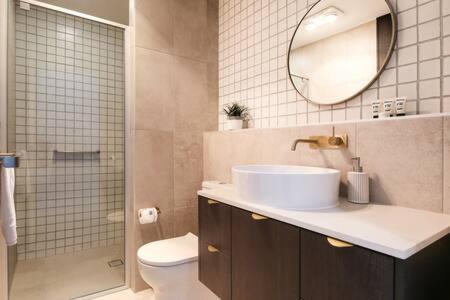 een badkamer met een wastafel, een spiegel en een toilet bij Elegant Bay Side 1-Bed Apartment with Views in Batemans Bay