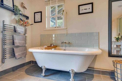 a large white tub in a bathroom with a window at Home sweet home in Little Wymondley