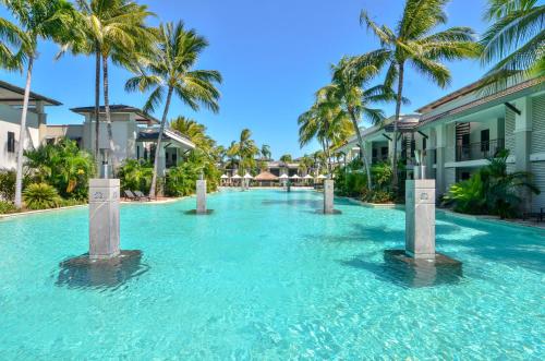 a swimming pool with palm trees in a resort at The Posh Penthouse With Stunning Rooftop Oasis, Free Parking And WIFI in Port Douglas