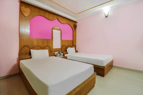 2 camas en una habitación con paredes rosas y blancas en OYO Hotel C K International, en Bodh Gaya