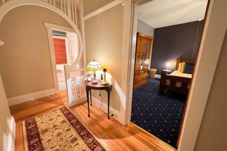 a room with a hallway with a table and a bed at Renovated Cottage Near Cataract Gorge Launceston in Royal Park