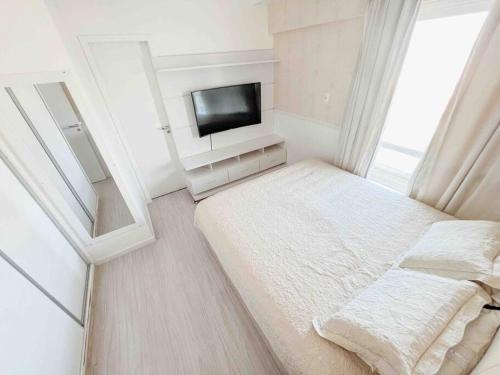 a small room with a bed and a tv at Apartamento com vista para o mar in Vitória