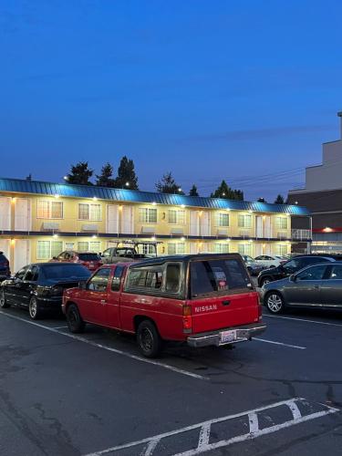 a red van parked in a parking lot in front of a building at Columbus Motor Inn in Seattle