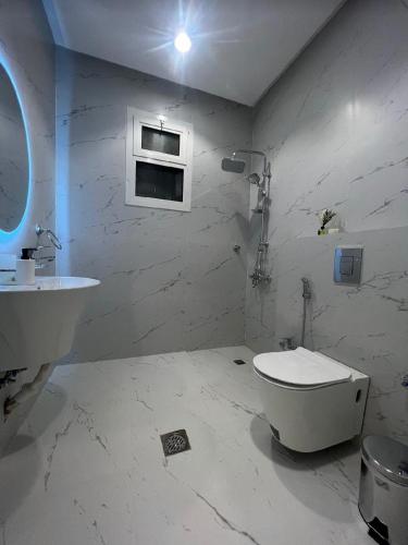 uma casa de banho branca com um WC e um lavatório em شقق سمارت انترى بالملقا em Riyadh