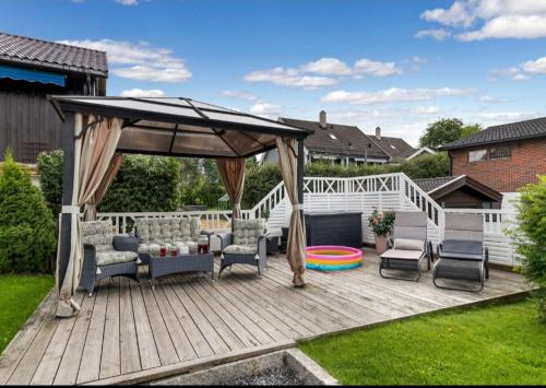 a wooden deck with a gazebo and chairs at God søvn in Lillestrøm