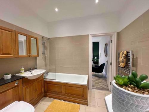 a bathroom with a tub and a sink and a toilet at INCREDIBLE 3 Bedrooms Windsor Home, Free Parking - A Blend of Luxury and Character - Incredible Location - Windsor Castle, Ascot, Legoland, Heathrow Airport in Windsor