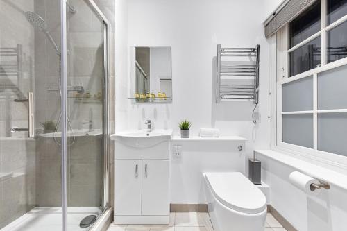 een witte badkamer met een douche, een toilet en een wastafel bij Modern One Bed Apartment - Sleeps 3 - Near Heathrow, Windsor Castle, Thorpe Park - Staines London TW18 in Staines upon Thames