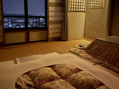 Cama grande en habitación con ventana en Kanko Ryokan Yamato en Ikuma