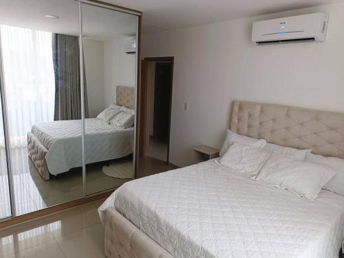 a bedroom with a large white bed and a mirror at Departamento Deluxe 2D in Santa Cruz de la Sierra