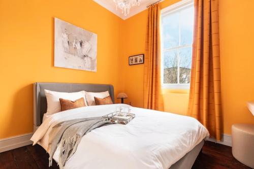 a bedroom with a bed with orange walls and a window at Stylish central London flat in London
