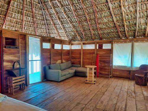 a living room with a couch and a straw roof at Cabañas Casa de Agua in Boca del cielo
