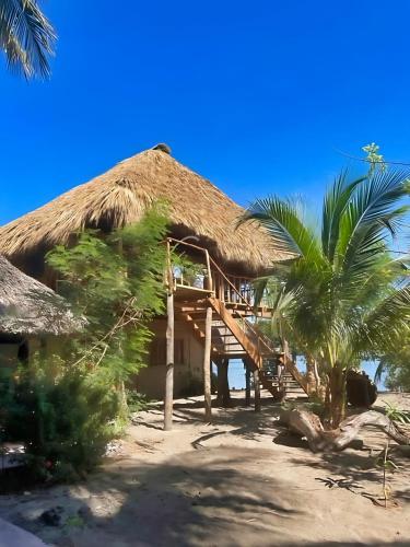 a house on the beach with a thatch roof at Cabañas Casa de Agua in Boca del cielo