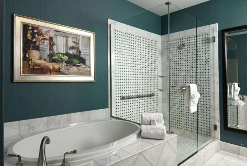 a bathroom with a tub and a glass shower at Woolley's Classic Suites Denver Airport in Aurora