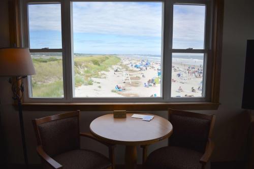 a room with a table and chairs and a view of a beach at Norseman Resort on the Beach in Ogunquit
