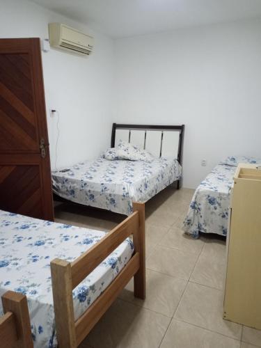 a room with three beds and a refrigerator in it at Vanessa pousada familiar in São Gabriel