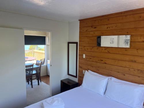 a bedroom with a bed with a wooden wall at Ranui Lodge in Mangonui