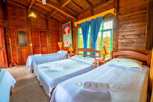 a bedroom with three beds in a wooden cabin at El ocaso in Quimbaya