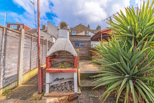 an outdoor oven in a yard next to a fence at Splendid Stays by Citybricks in Kent