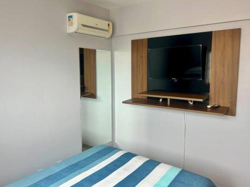 a bedroom with a bed and a tv on a wall at Ap de 2 q, 70 metros, em bairro nobre e central in Goiânia