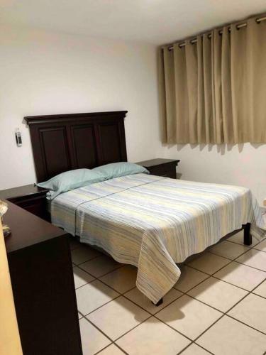 a bedroom with a bed with a wooden headboard at 302 Excelente apto muy Cerca de Playa in Mazatlán