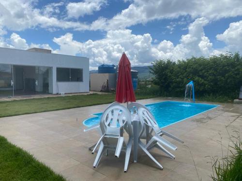 twee stoelen en een parasol naast een zwembad bij Residencial linda vista casa azul in Mateus Leme