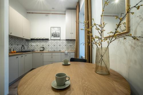 a wooden table with two cups and a vase on it at Apartament Gold Próchnika 9 in Łódź