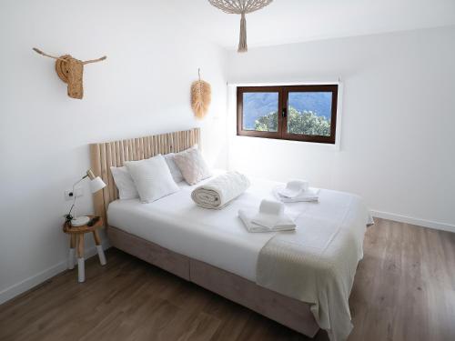 a white bedroom with a large bed with a window at Hostel Retiro do Gerês in Geres