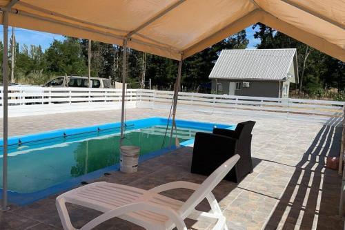 a swimming pool with a tent and chairs next to it at Casa en salto del Laja in El Manzano