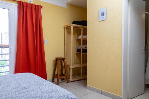 1 dormitorio con cama y cortina roja en Un lugar cómodo y céntrico en General Sarmiento